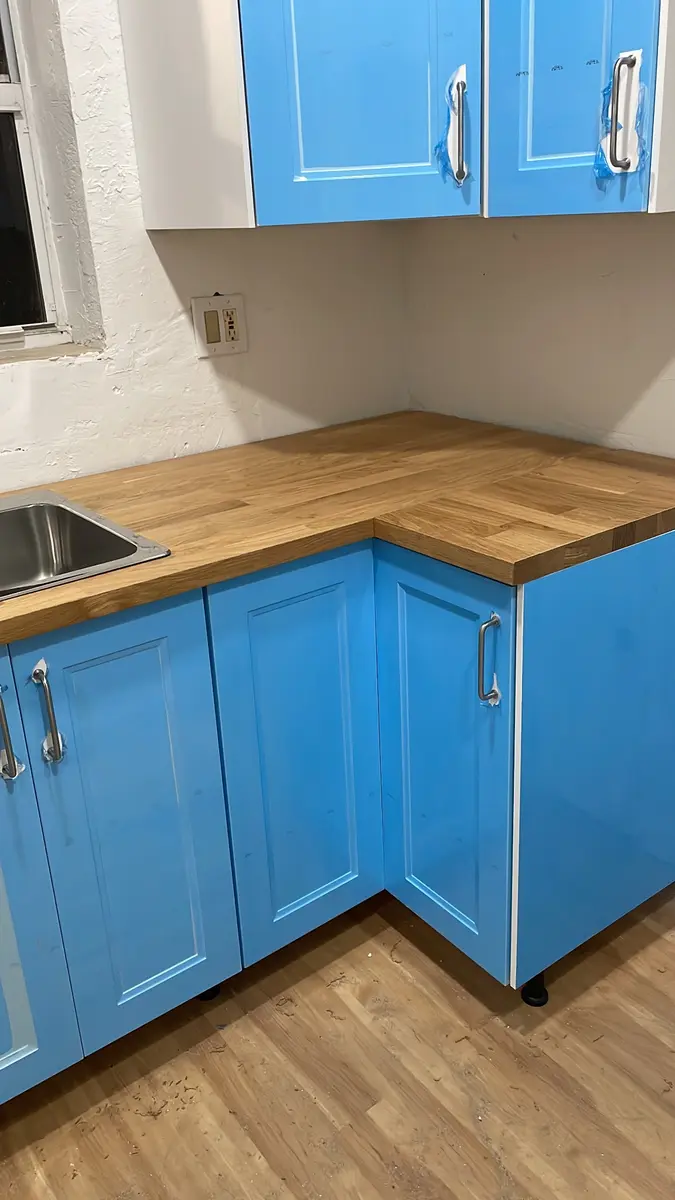 Wood countertop fitted around blue base cabinets