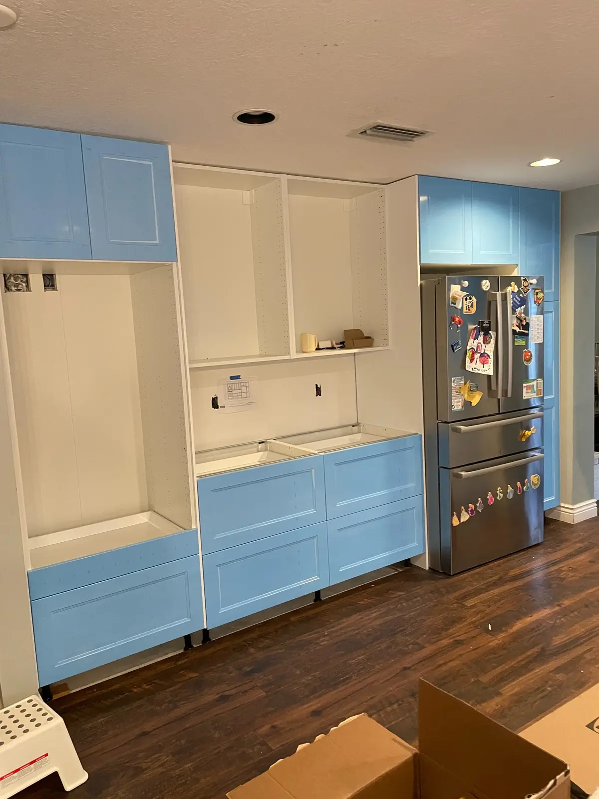 Full wall of blue and white kitchen cabinetry during installation
